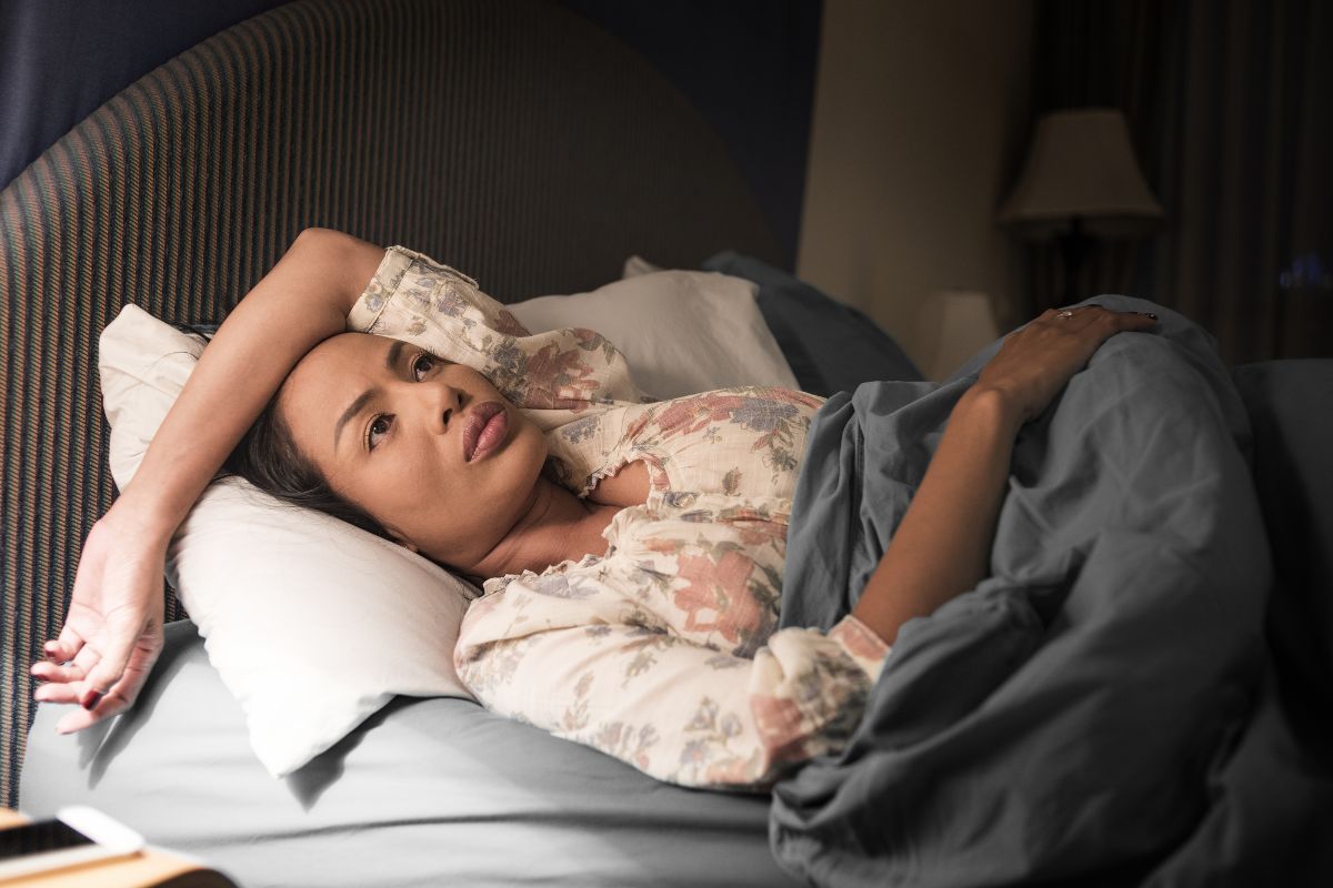 Woman lying awake in bed at night, unable to sleep despite being tired